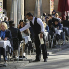 Un camarero sirve unas mesas en un restaurante.