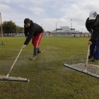 Dos operarios trabajan sobre el césped del estadio maragato.