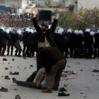 Un hombre pide ayuda mientras seguidores palestinos de Hamas lanzan piedras a la policía