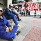 Varios mineros sentados, al paso de la manifestación de la huelga general.