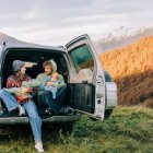 Viajar por carretera permite descubrir destinos a otro ritmo y disfrutar de experiencias al aire libre en familia, combinando paisaje, libertad y aventura. family enjoying mountain scenery from car trunk during road trip