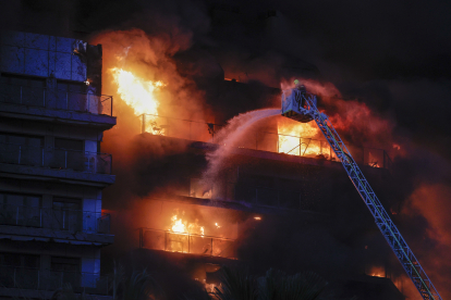 Bomberos trabajan en el incendio declarado sobre las cinco y media de esta tarde en un quinto piso de un edificio de viviendas de Valencia.