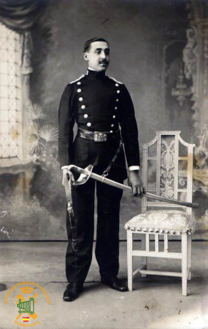 Guardia civil del 10º tercio (León y Palencia), con uniforme de diario en población (reglamento 1909), posando en un estudio de fotografía, portando en sus manos un sable modelo 1880-1888 para tropa de caballería.