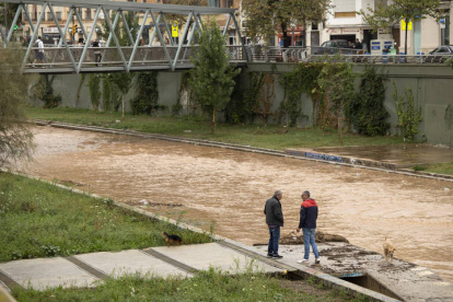 Varias personas observan el río Guadalmedina a su paso por Málaga capital que se encuentra cubierto de agua por las fuertes lluvias caídas en las últimas horas debido al paso de la dana por Andalucía que está dejando innumerables incidencias.