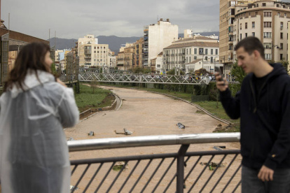 Dos personas fotografían el estado del río Guadalmedina a su paso por Málaga capital que se encuentra cubierto de agua por las fuertes lluvias caídas en las últimas horas debido al paso de la dana por Andalucía que está dejando innumerables incidencias.