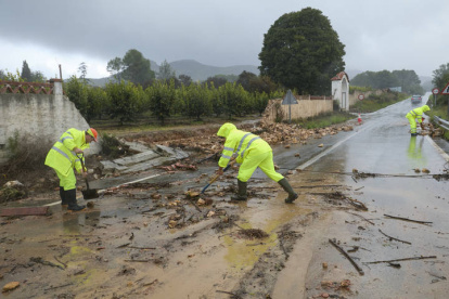 Unos operarios limpian la carretera de acceso a Manuel cortada debido a las lluvias torrenciales que afectan a la Comunitat Valenciana, y especialmente a la provincia de Valencia.