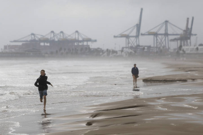 Dos personas pasean por la playa de la Malvarrosa durante este martes en el que las lluvias torrenciales afectan a la Comunitat Valenciana.