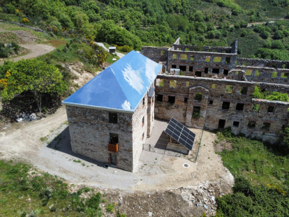 El tejado de aluminio-espejo atrapa las nubes en el antiguo economato del poblado de La Piela, reconvertido en el centro de visitantes La Montaña Negra. 