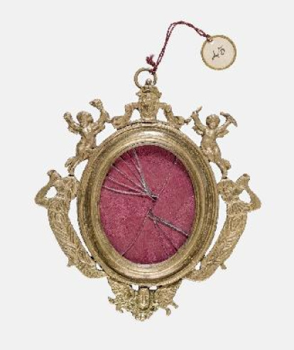 Marco de medallón parietal, con anilla movible en la parte superior. Está fundido en bronce, con moldura interior ovalada rodeada por motivos ornamentales recortados y calados: un escudo en el remate superior del eje vertical, al que está unida la anilla, y de forma simétirca hacia abajo, dos angelotes o genios alados, llevando cornetas y otro objeto en las manos, y dos figuras híbridas entre salvajes y sirenas, que tocan cornetas; y en la parte inferior del eje vertical, un querubín. Ingresó en el Museo Arqueológico Nacional con el viril de vidrio ya roto y sin su contenido, que pudo ser una imagen devocional pintada o grabada sobre papel. Obra procedente de la colección de Carlos Walter Heiss (1885-?), entregada en calidad de depósito por la Comisaría General del Patrimonio Artístico Nacional, el 15 de diciembre de 1942.