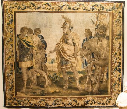 Tapiz con cenefa de guirnaldas y frutos que enmarca una escena protagonizada por varios guerreros romanos: los tres del lado derecho se alejan del personaje que ocupa el centro, entrado en años y barbado, vestido con manto, armadura, casco con penacho, que lleva bastón de mando; a su espalda, en el lado izquierdo, otro tres soldados llevan armadura, casco, lanza, estandartes y uno sujeta un caballo. Obra entregada al Museo Arqueológico Nacional en calidad de depósito por la Comisaría General del Patrimonio Artístico Nacional, el 9 de octubre de 1951.
