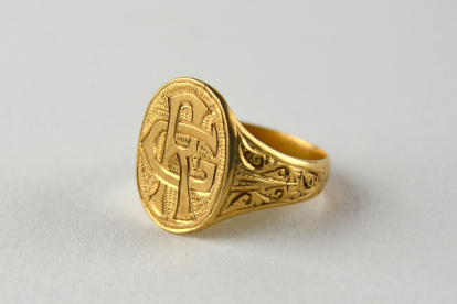 Anillo de oro con sello ovalado con las iniciales RG sobre fondo estriado. El aro es plano el cual se ensancha en su llegada al sello. Los laterales poseen volutas y formas geométricas, presentando el lado derecho un mayor desgaste. Datado entre 1888 y 1940. Obra entregada en calidad de depósito por el Ministerio de Cultura al Museo Nacional de Cerámica, el 23 de septiembre de 1978.