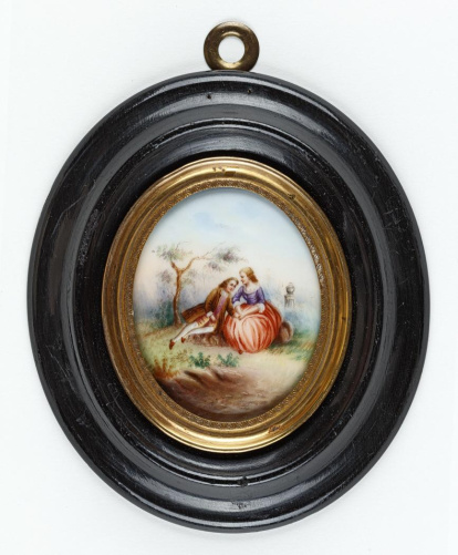 Miniatura oval con escena galante en la que una dama sentada, vestida con corpiño morado rematado en encaje y falda encarnada, sostiene entre sus manos la mano de un muchacho que se sienta a su derecha, con casaca y pantalones marrones, chaleco violeta y medias blancas. Segunda mitad del siglo XVIII. Obra entregada en calidad de depósito por la Comisaría General del Patrimonio Artístico Nacional el 18 de junio de 1943.