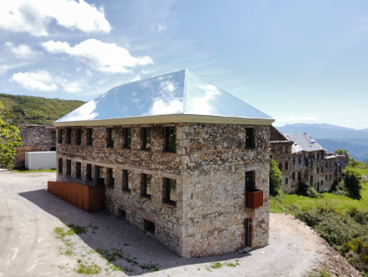 El tejado de aluminio-espejo atrapa las nubes en el antiguo economato del poblado de La Piela, reconvertido en el centro de visitantes La Montaña Negra