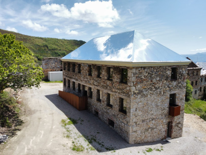 El tejado de aluminio-espejo atrapa las nubes en el antiguo economato del poblado de La Piela, reconvertido en el centro de visitantes La Montaña Negra