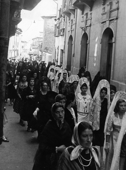 La procesión recorre la calle Diego Antonio González. En primer plano, grupo de mujeres ponferradinas ataviadas con mantillas y trajes típicos bercianos.