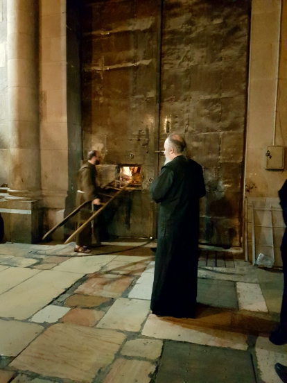 Momento en el que se pasa a través de una pequeña ventana la escalera para acceder a la cerradura por la que se abre desde dentro la tumba de Jesucristo en Jerusalén.